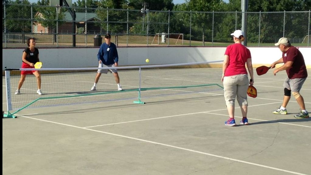 A pickleball player readies his paddle for the ball as a teammate stands beside him