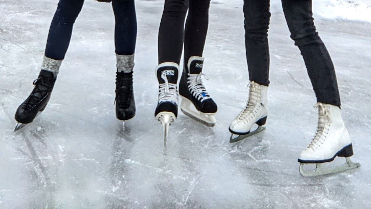 Three ice skaters on an outdoor rink