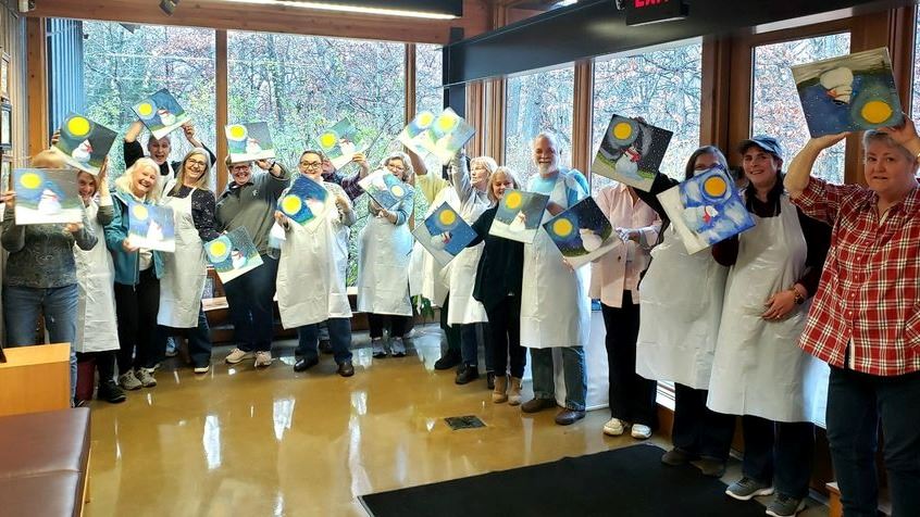 Group of painters hold up their art