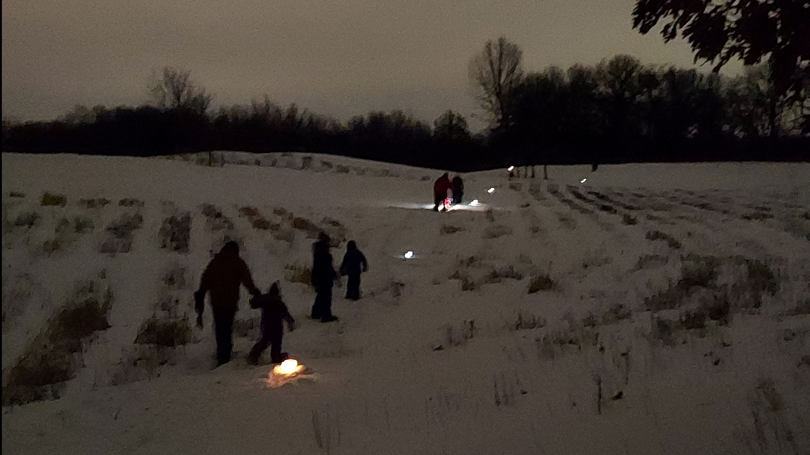 Families snowshoe a luminary night trail